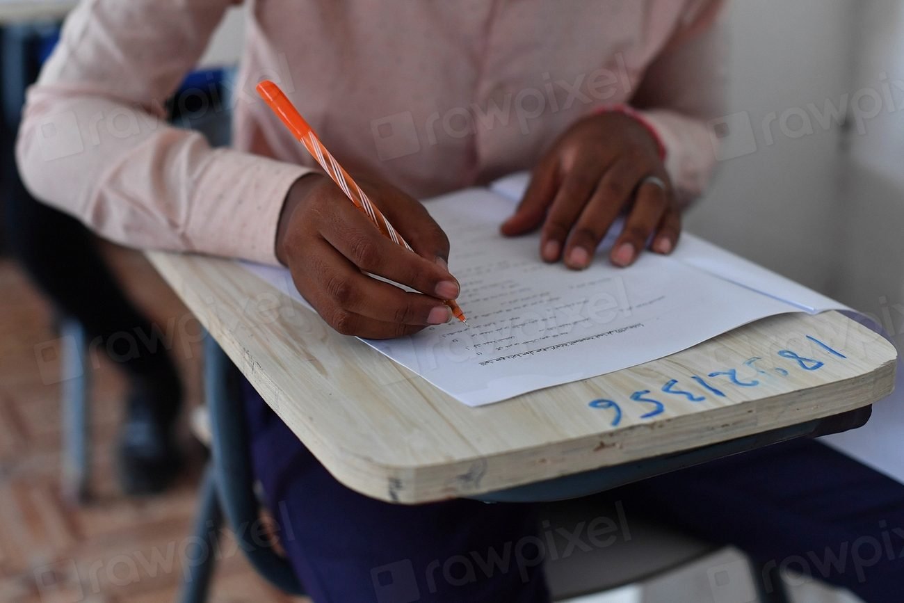 Secondary school students sitting at desks writing answers during an exam