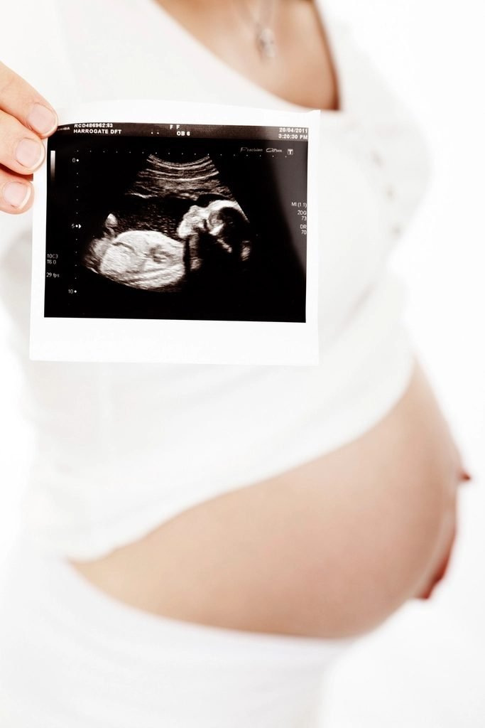 Pregnant woman holding her bare belly, representing tracking a pregnancy toward its due date