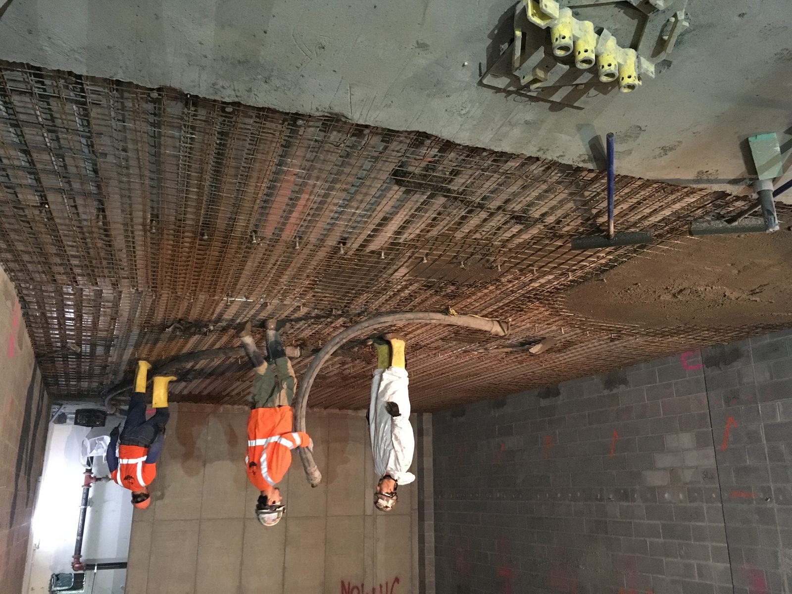 Construction workers pouring and finishing a concrete floor slab on a job site