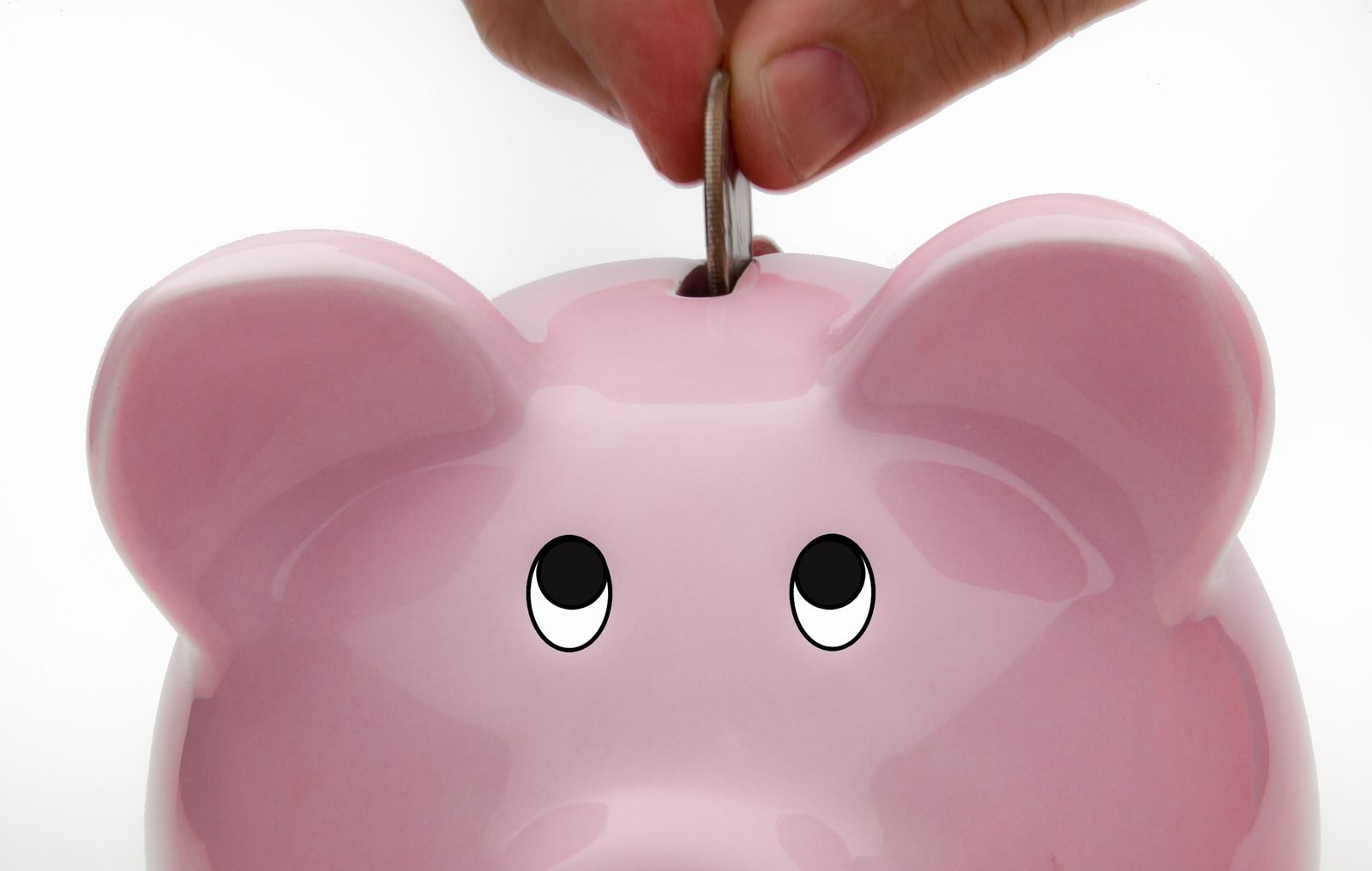 Hand dropping a coin into a piggy bank to build up long-term retirement savings