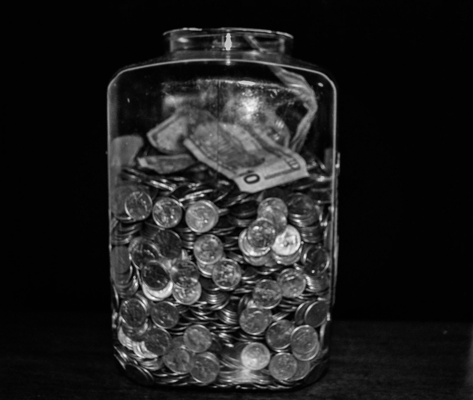 Glass tip jar filled with cash and coins left for service staff