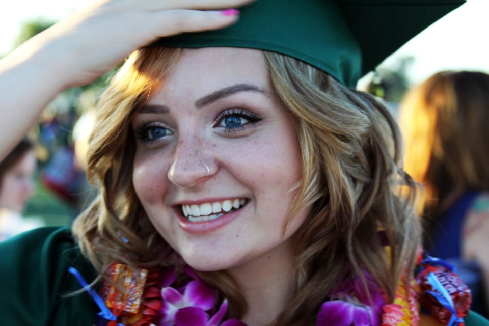 Graduate in cap and gown smiling while holding a diploma