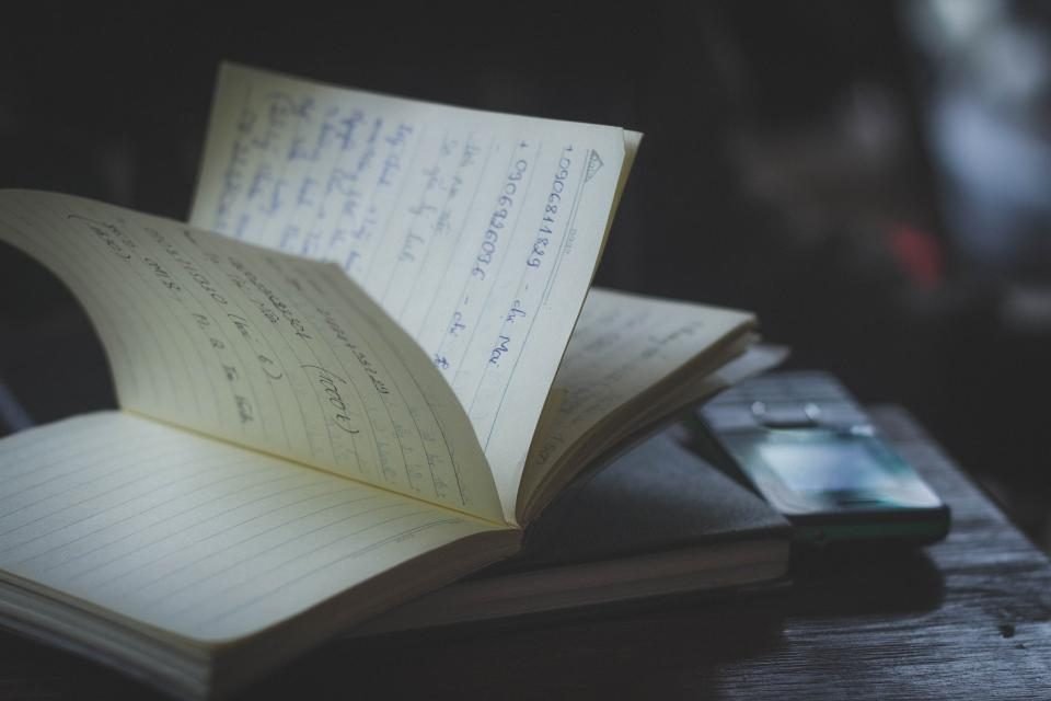 Open notebook with handwritten notes on a wooden desk
