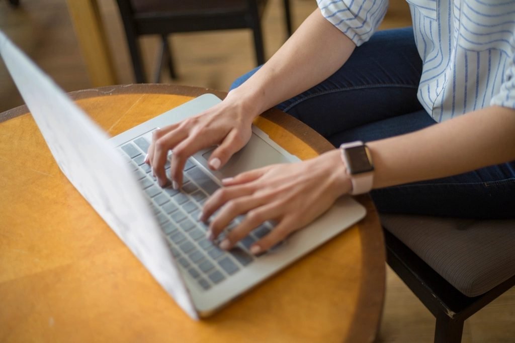 Close-up of a person's hands typing an email on a laptop keyboard
